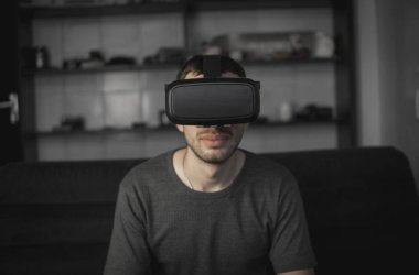 Kanepede oturan Office sanal gerçekliğin kulaklık giyen adam Genç sakallı.