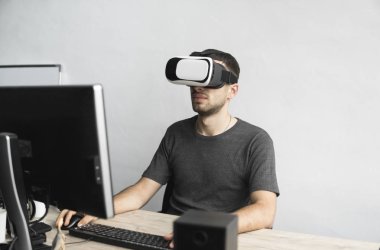 Sanal gerçeklik giyen genç adam kulaklık, vr kutusu ve bilgisayar monitörü karşı ofiste oturan gözlükler. Bağlantı, teknoloji, yeni nesil, ilerleme kavramı.