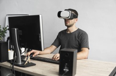 Sanal gerçeklik giyen genç adam kulaklık, vr kutusu ve bilgisayar monitörü karşı ofiste oturan gözlükler. Bağlantı, teknoloji, yeni nesil, ilerleme kavramı.