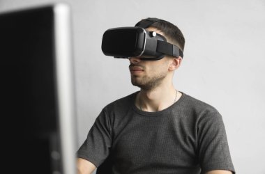 Sanal gerçeklik giyen genç adam kulaklık, vr kutusu ve bilgisayar monitörü karşı ofiste oturan gözlükler. Bağlantı, teknoloji, yeni nesil, ilerleme kavramı.