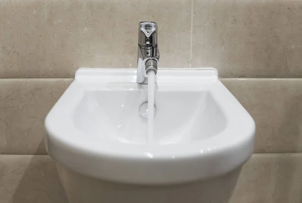 Détails du bidet en céramique blanche avec eau courante dans la salle de bain moderne . — Photo