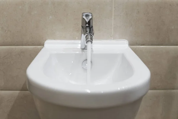 Details of white ceramic bidet with a running water in modern bathroom. — Stock Photo, Image