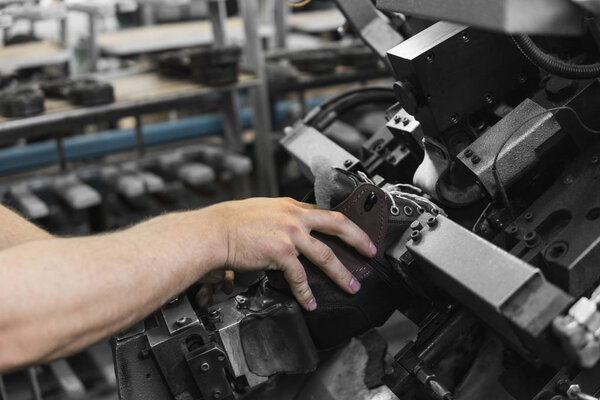 Man use special machine tool for making a shoes. The conveyor on a shoes factory with shoe and sole. Mass production of footwear.
