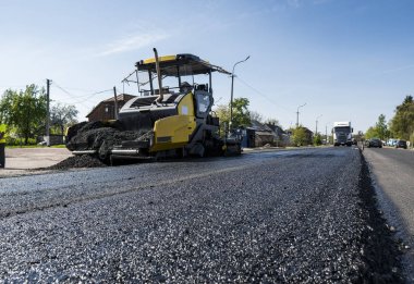 Asfalt Finişer makine yol yapımı sırasında işletim ve tamir işçi çalışıyor. Bir fayans ustası son işlemci, asfalt tamamlayıcı veya kaldırım makine asfalt tabakası yerleştirerek. Asfaltlanması