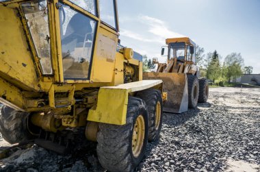 Sarı yükleyici boş kova ile bir taş çakıl yol inşaat çalışmaları sırasında duruyor. Yolun taşları. Boşaltma taş.