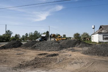 Sarı yükleyici boş kova ile bir taş çakıl yol inşaat çalışmaları sırasında duruyor. Yolun taşları. Boşaltma taş.