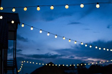 Satır yaz teras ışıklar akşam, küçük açık Işık Ampüller sırasında asılı.