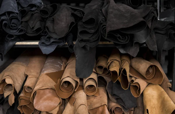 Different pieces of leather in a rolls. The pieces of the colored leathers. Rolls of natural brown and black and other leather. Raw materials for manufacture of bags, shoes, clothing and accessories.