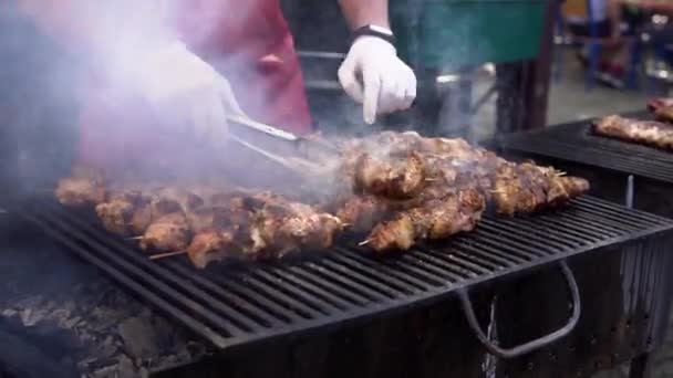 Man koken vlees op barbecue grill voor zijn vrienden in zomer outdoor Party. Koken varkensvlees op hete houtskool. Close-up van traditionele picknick gerecht. Grillen van vlees op hout kolen. — Stockvideo