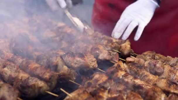 Man koken vlees op barbecue grill voor zijn vrienden in zomer outdoor Party. Koken varkensvlees op hete houtskool. Close-up van traditionele picknick gerecht. Grillen van vlees op hout kolen. — Stockvideo