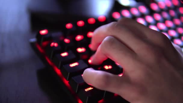 Gros plan sur la rangée de joueurs mains sur un clavier, appuyer activement sur les boutons, jouer à des jeux MMO en ligne. L'arrière-plan est lumineux avec des néons . — Video