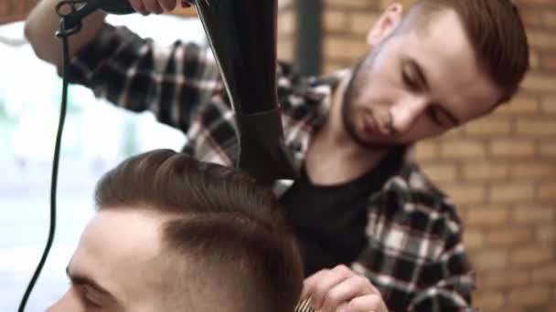 Close-up em Mens hairstyling e corte de cabelo em uma barbearia ou salão de cabeleireiro usando tesoura e secador de cabelo. A arrumar o cabelo. Barbearia . — Vídeo de Stock