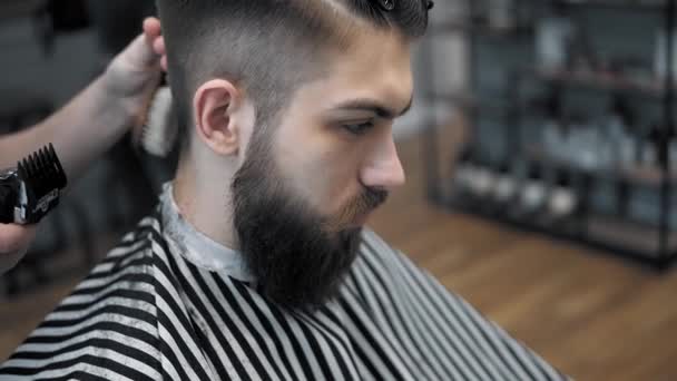 Vista de cerca en los hombres peinado en una peluquería con trimmer profesional. Corte de pelo para hombre en peluquería con cortador eléctrico. Aseo del cabello . — Vídeo de stock