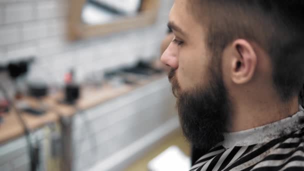 Vista close-up no penteado masculino em uma barbearia com aparador profissional. Corte de cabelo Mans no salão de cabeleireiro com cortador elétrico. Arrumar o cabelo . — Vídeo de Stock