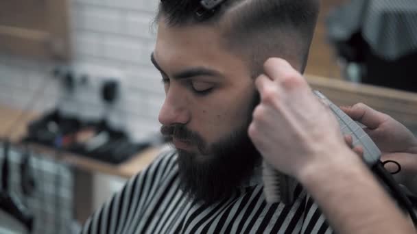 Γκρο πλαν θέα στο αρσενικά χτένισμα στο κουρείο με επαγγελματικό trimmer. Mans haircutting στο κομμωτήριο με ηλεκτρική κουρευτική μηχανή. Περιποίηση μαλλιών. — Αρχείο Βίντεο