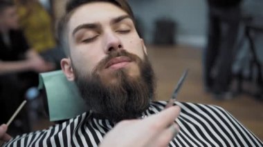 Yapıyor Kuaför saç kesimi ile yetişkin erkekler erkek kuaför salonu içinde uzun sakallı sakallar. Sakal bakım. Salonların işyerinde. Sakal saç şekillendirme ve kanununu bir kuaför dükkanında.