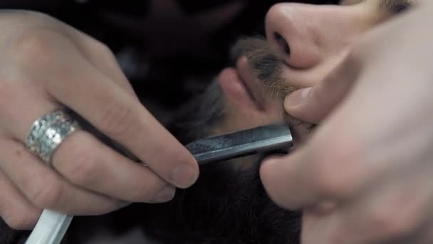 Friseur rasiert Männer mit langem Bart mit Rasierklinge im Friseursalon oder Friseursalon. Herrenfrisur und Rasur beim Friseur, Friseur und Rasiersalon. — Stockvideo