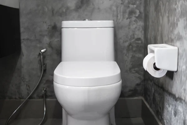 Vit hängande toalettsits på vit toalett i hemmet badrum med grå kakel i betong stil och toalettpapper på väggen. Badrum lyx interiör. — Stockfoto
