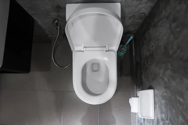 Asiento de inodoro colgante blanco en inodoro blanco en el baño de la casa con azulejos grises en estilo concreto y papel higiénico en la pared. Baño interior de lujo . — Foto de Stock