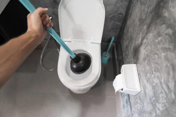 Toalett reparation för hand med en toalett kolv. Vvs. En rörmokare använder en kolv för att rensa en toalett. Toalett kolv. — Stockfoto