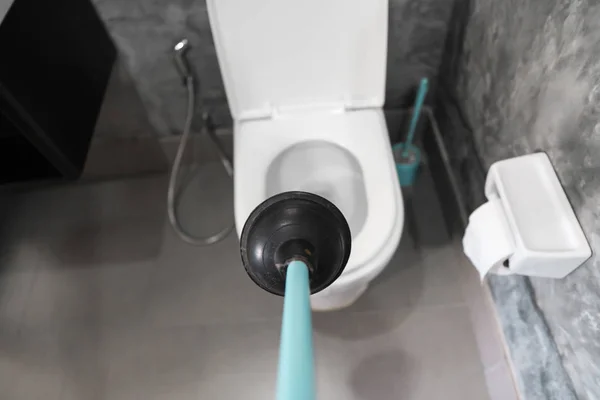 Reparação de vaso sanitário à mão com um êmbolo de vaso sanitário. Encanamento. Um canalizador usa um êmbolo para desentupir uma sanita. êmbolo sanitário . — Fotografia de Stock