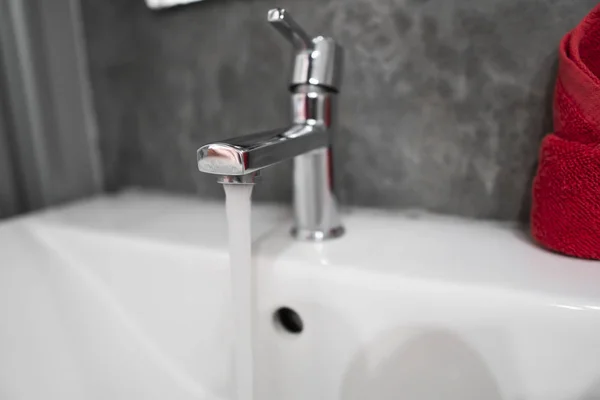 Вода из современных кранов из нержавеющей стали в белой раковине. Интерьер в ванной комнате современный. Роскошная и стильная ванная комната с бетонными стенами . — стоковое фото