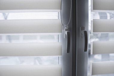 Pencere sapı ve beyaz kumaş rulo oturma odasında beyaz plastik pencereüzerinde jaluz. Rulo perdeleri kapalı kapatın.