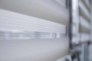 Oturma odasında beyaz plastik pencereüzerinde beyaz kumaş rulo jaluman detayları. Rulo perdeleri kapalı kapatın.