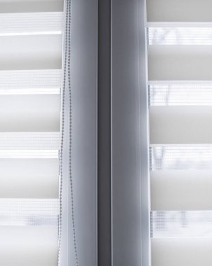 Oturma odasında beyaz plastik pencereüzerinde beyaz kumaş rulo jaluman detayları. Rulo perdeleri kapalı kapatın.