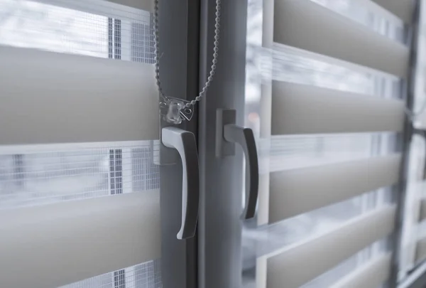 Window handle and white fabric roller blinds on the white plastic window in the living room. Close up on roll curtains indoor. — Stock Photo, Image