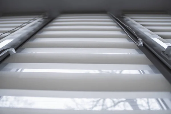 Détails des stores à rouleaux en tissu blanc sur la fenêtre en plastique blanc dans le salon. Fermer sur les rideaux de rouleau intérieur . — Photo