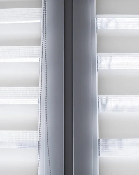 Details of white fabric roller blinds on the white plastic window in the living room. Close up on roll curtains indoor. — Stock Photo, Image