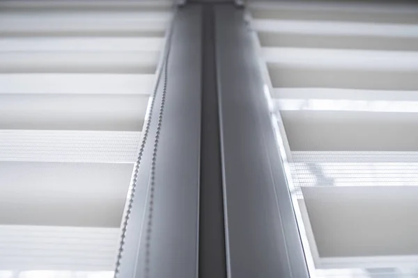 Details of white fabric roller blinds on the white plastic window in the living room. Close up on roll curtains indoor. — Stock Photo, Image
