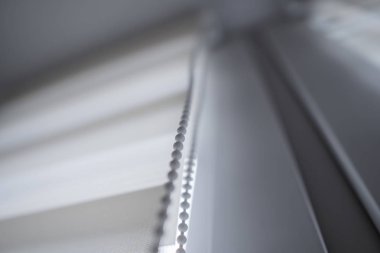 Oturma odasında beyaz plastik pencereüzerinde beyaz kumaş rulo jaluman detayları. Rulo perdeleri kapalı kapatın.