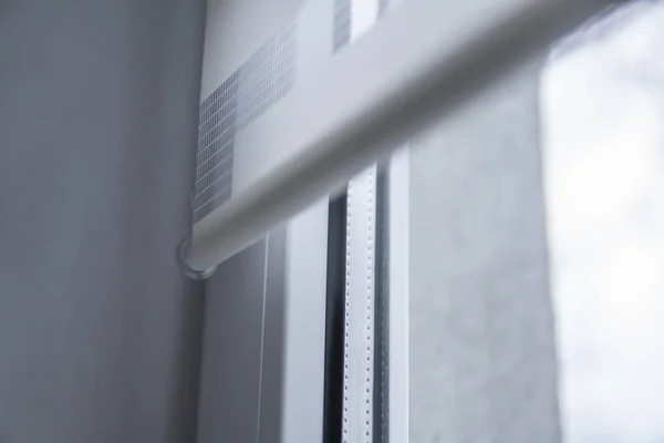 Деталі білих тканинних ролет на білому пластиковому вікні у вітальні. Крупним планом на рулонних шторах в приміщенні . — стокове фото