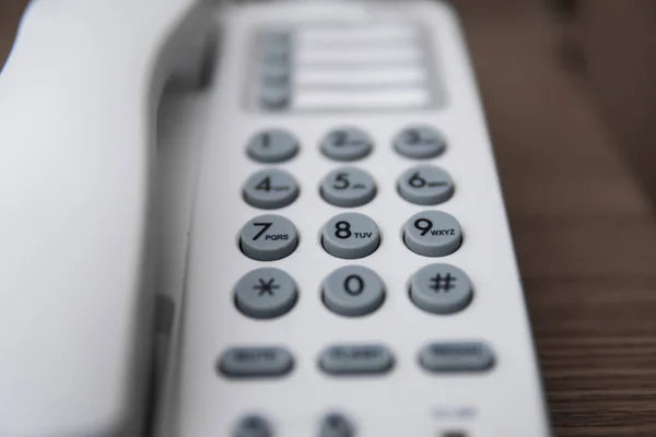 Vit Vintage telefon med gråa bataloder på ett brunt bord på hotellet. — Stockfoto