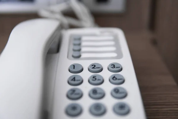 Vit Vintage telefon med gråa bataloder på ett brunt bord på hotellet. — Stockfoto