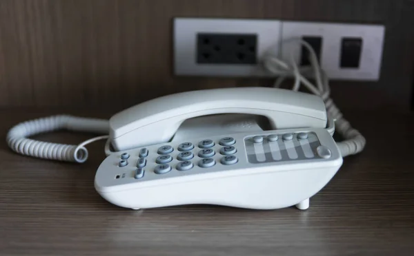 Otelde kahverengi bir masada gri coplar ile beyaz vintage telefon. — Stok fotoğraf