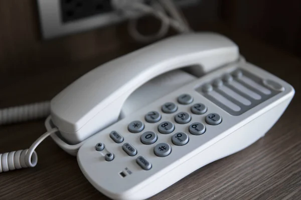 Vit Vintage telefon med gråa bataloder på ett brunt bord på hotellet. — Stockfoto