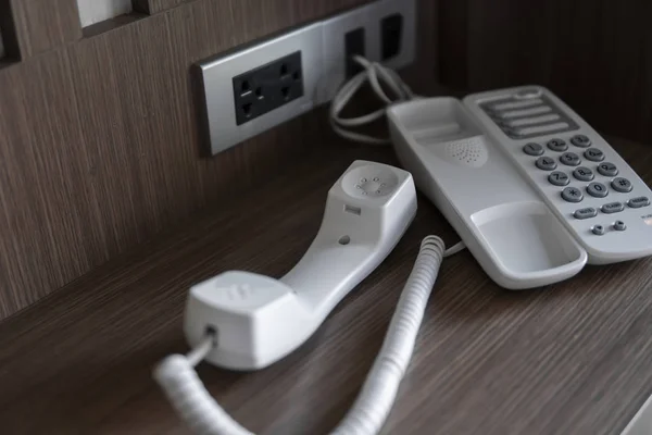 Otelde kahverengi bir masada gri düğmeli beyaz vintage telefonun kulaklığı çıkarın. — Stok fotoğraf