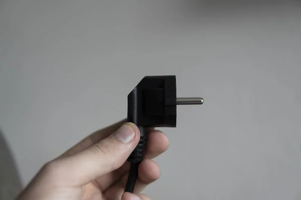 Tapón eléctrico negro de mano sobre fondo gris . — Foto de Stock