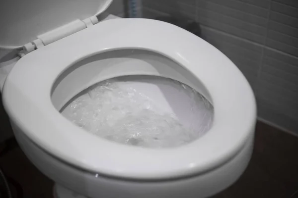 White hanging toilet seat on white toilet in the home bathroom with grey tiles. — Stock Photo, Image