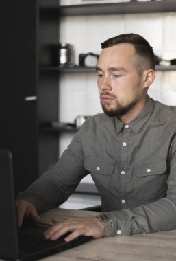 Genç işadamı ya da öğrenci bilgisayar monitörü karşı oturan bir gömlek. Düşünceli bir ifade ile ofiste bir masada bir pc üzerinde çalışıyor. Ofiste dizüstü bilgisayar üzerinde çalışan genç işadamı.
