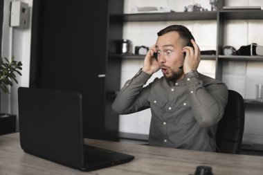 Etkilendim mutlu gülümseyen Genç işadamı ya da öğrenci bir gömlek kulaklık bilgisayar monitörü karşı oturan ve internet üzerinden biriyle konuşan. Ofisteki bir masada bir bilgisayar üzerinde çalışmak.