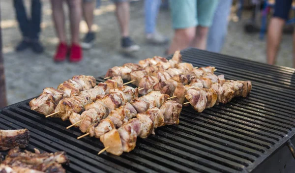 Delicious bbq grilling meat on open grill, outdoor kitchen. Food festival in city. tasty food roasting on skewers, food-court. Summer picnic.