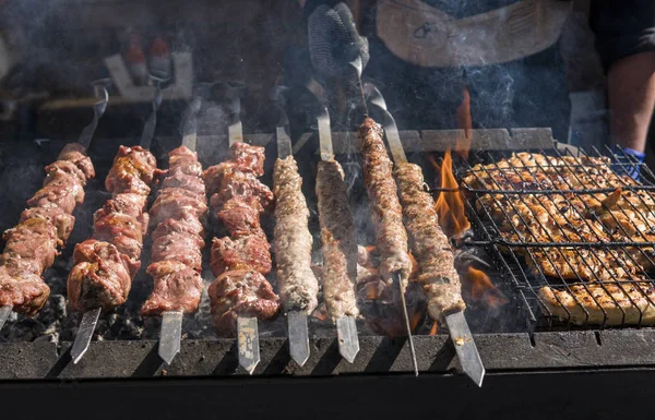 Delicious bbq grilling meat on open grill, outdoor kitchen. Food festival in city. tasty food roasting on skewers, food-court. Summer picnic.