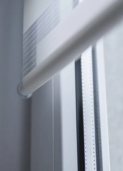 Детали белых тканевых роликов жалюзи на белом пластиковом окне в гостиной. Закрыть шторы в помещении . — стоковое фото