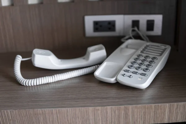 Otelde kahverengi bir masada gri düğmeli beyaz vintage telefonun kulaklığı çıkarın. — Stok fotoğraf
