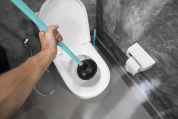 Réparation des toilettes à la main avec un piston de toilette. Plomberie. Un plombier utilise un piston pour déboucher les toilettes. Pistolet de toilette . — Photo