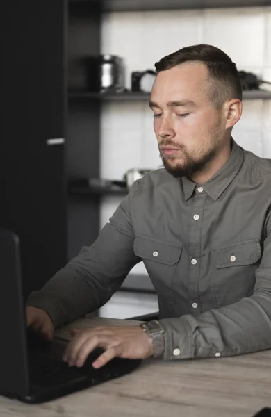 年轻的商人或学生穿着衬衫坐在电脑显示器上。在办公室的桌子上用一张电脑，用深思熟虑的表情。年轻的商人在办公室工作，他的笔记本电脑. — 图库照片